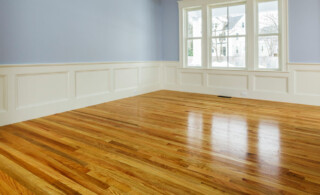 Hardwood floors in living room with a window and no furniture.