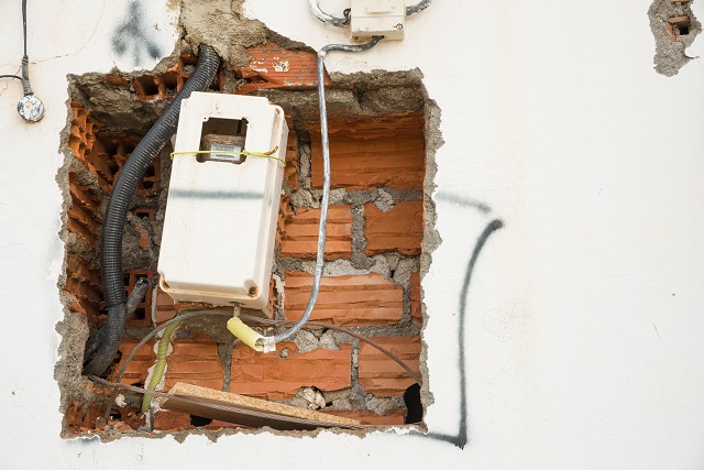 Unfinished wiring and electricity meter on a wall