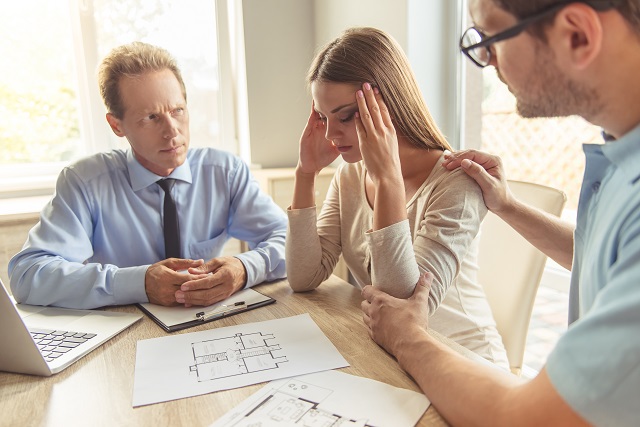 Frustrated couple consulting with professional about home blue prints