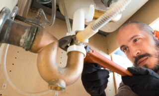 Plumber working under sink