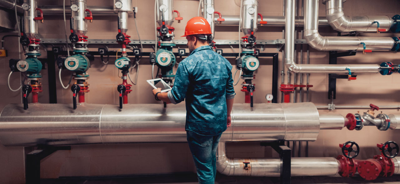 Pipefitter at work checking tablet