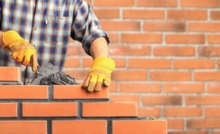 mason lays plaster between brick