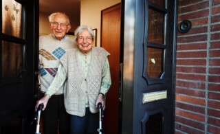 elderly couple opening the front door