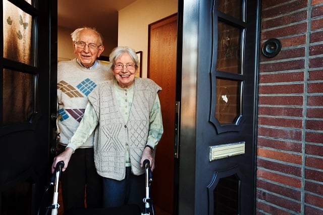 elderly couple opening the front door