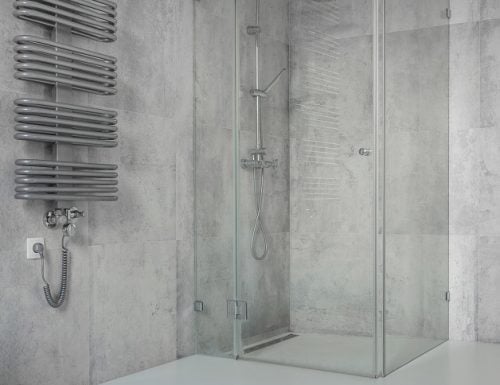 Spacious, modern, minimalist bathroom with concrete tiles and glass shower cabin