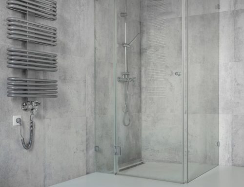 Spacious, modern, minimalist bathroom with concrete tiles and glass shower cabin
