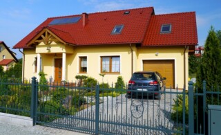 yellow house with red roof and aluminum fence