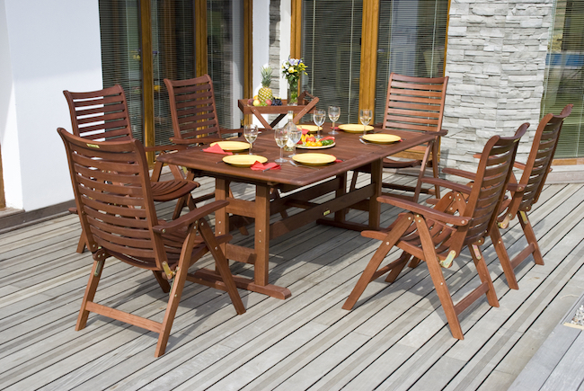 An outdoor table set for dinner on a wooden deck.