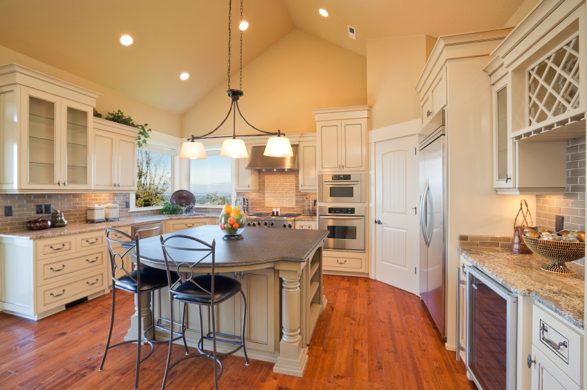A warmly lighted kitchen with an island and a wine fridge.
