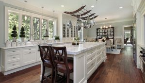 A bright kitchen with white marble countertops and wooden chairs.