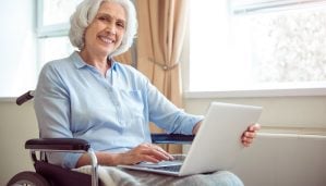Digitalization. Cheerful and positive senior woman in wheelchair using laptop
