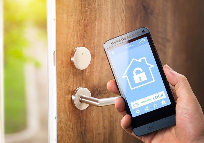 smart house, home automation, device with app icons. Man uses his smartphone with smarthome security app to unlock the door of his house.