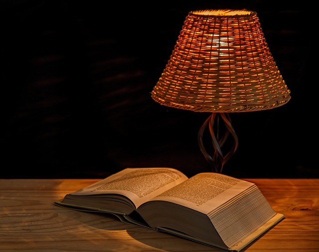 soft light lamp over open book on wooden desk