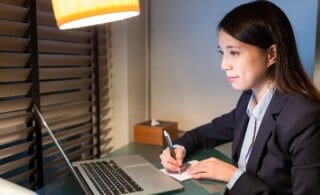 personal assistant writing on the note with laptop computer