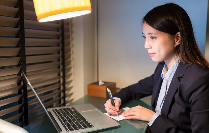 personal assistant writing on the note with laptop computer