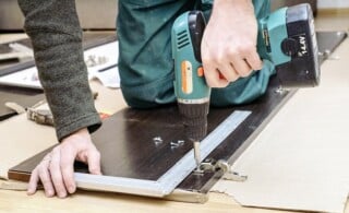 Assembling furniture from chipboard, using a cordless screwdriver, close up.