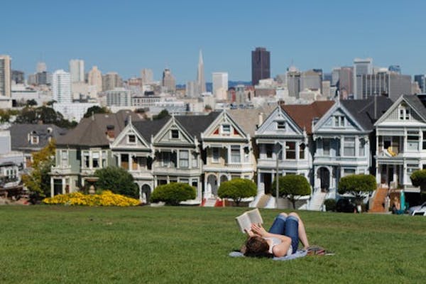 Reading a book in Golden Gate Park across from the row houses in California.