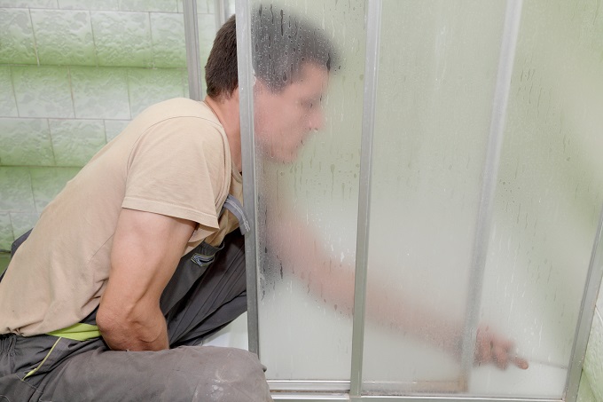 Plumber installing a shower cabin in bathroom