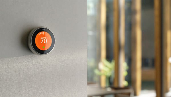 A smart thermostat controls the temperature on a wall.