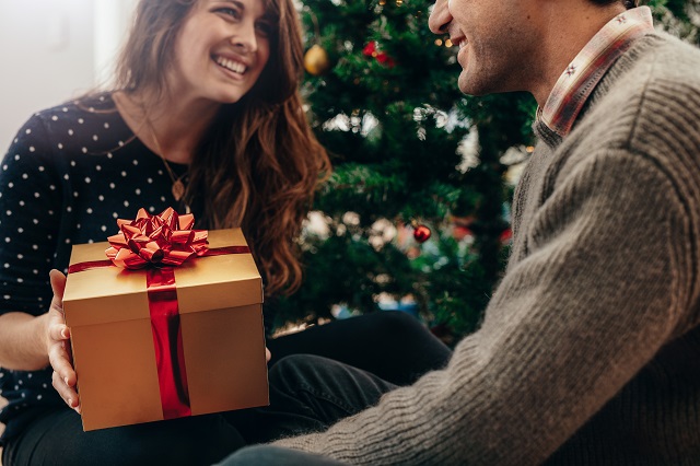 Young couple celebrating Christmas by exchanging gifts.