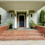 Painted black door in large entrance porch with columns and brick trim