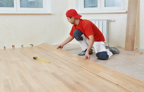 carpenter worker installing wood parquet board during flooring work with hammer