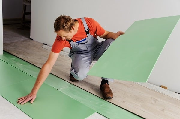 Worker puts the pieces underlayment for subsequent installation of laminate flooring