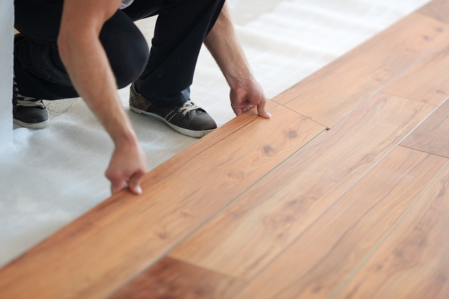 Young woman installing laminate flooring