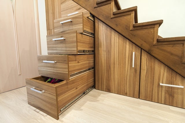 Modern architecture interior with luxury hallway with glossy wooden stairs in modern storey house. Custom built pullout cabinets on glides in slots under stairs