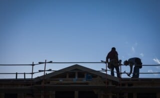 Construction Workers Silhouette on Roof of Building.