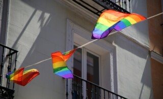 Rainbow flags hanging from the balconies of an old house