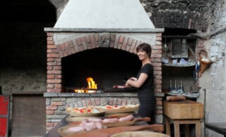 Woman grilling in front of an outdoor wood fireplace