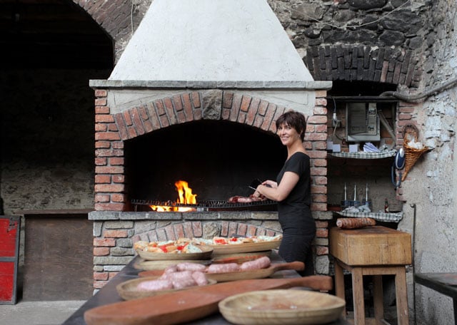 Woman grilling in front of an outdoor wood fireplace