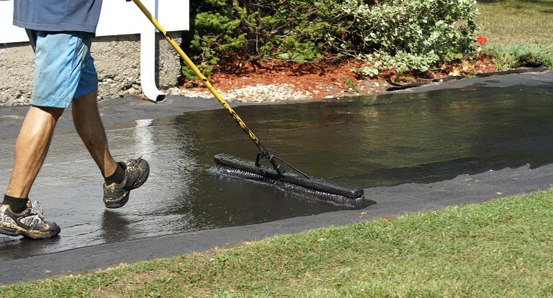 sealing an asphalt driveway with a brush