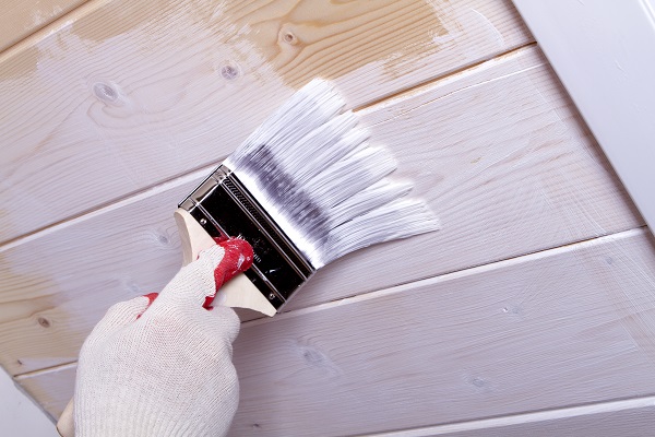 gloved hand paint wooden ceiling linings in white