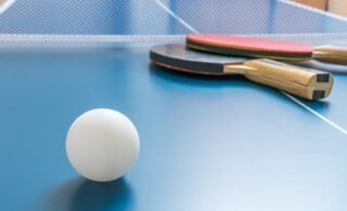 White ball for table tennis or ping pong on wooden table.