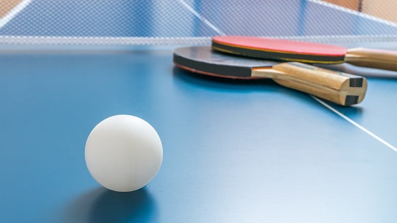 White ball for table tennis or ping pong on wooden table.