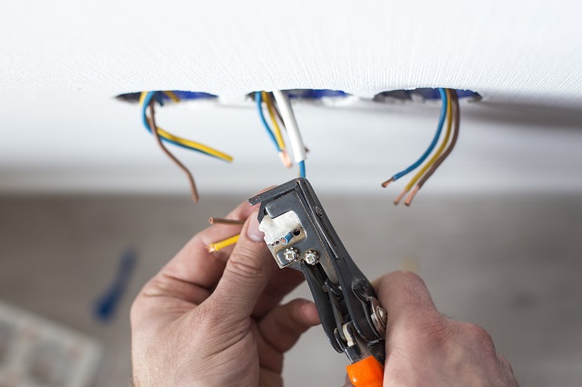 Electrician stripping insulation from wire for installation an electrical outlet