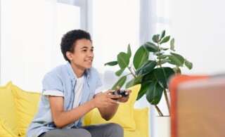 Teenager playing video games at home alone