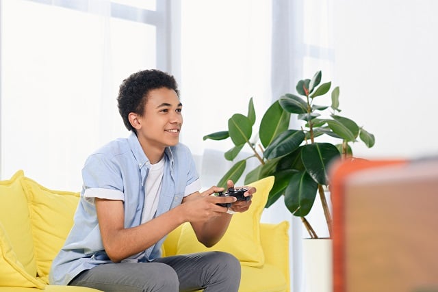 Teenager playing video games at home alone