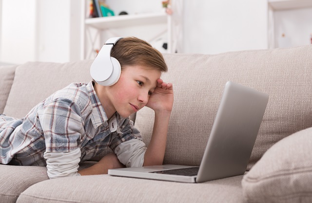 Teenage boy on laptop at home alone