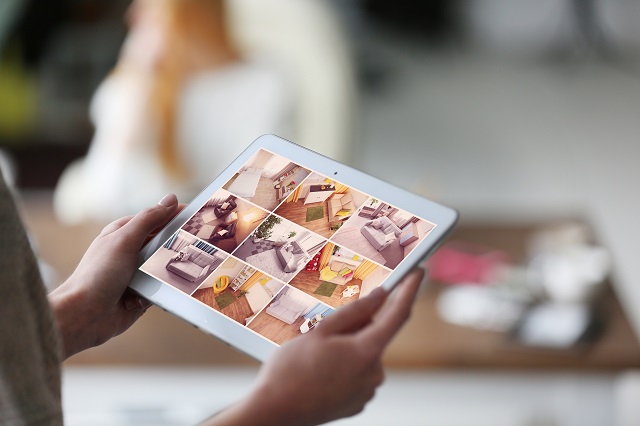 Woman monitoring home security system cameras' live view on a tablet display