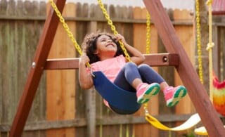 Kid toddler girl swinging on a playground swing