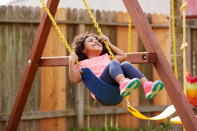 Kid toddler girl swinging on a playground swing