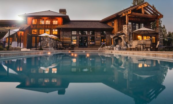 beautiful large home with pool at dusk with lights on