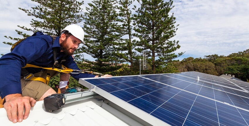 man installs solar panel on roof