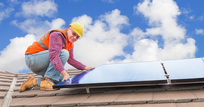 elder man installs solar panels on a home