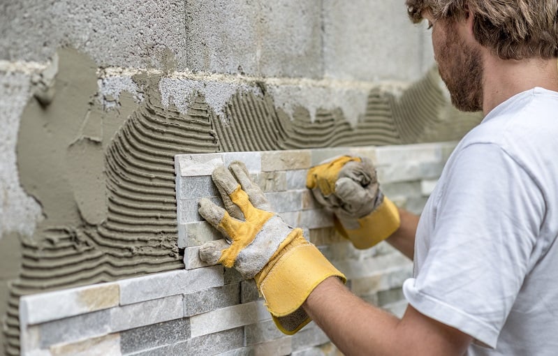 professional installs tile onto a wall