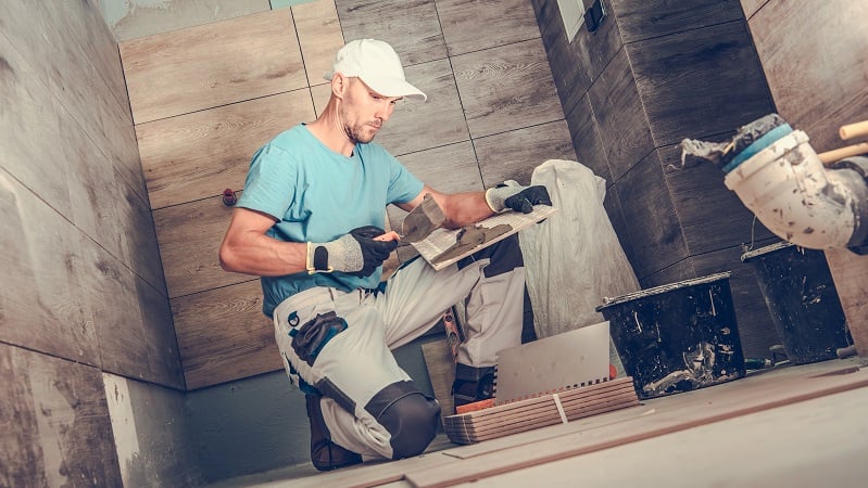 man applies tile during a bathroom remodel