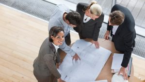 architects review blueprints with draftswoman